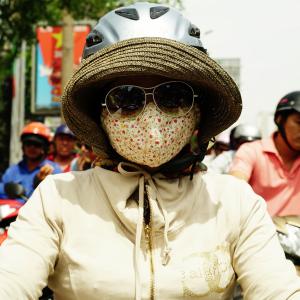 Girl with beige "Cover-up style" driving on the streets of H.C.M.C. Girl with beige